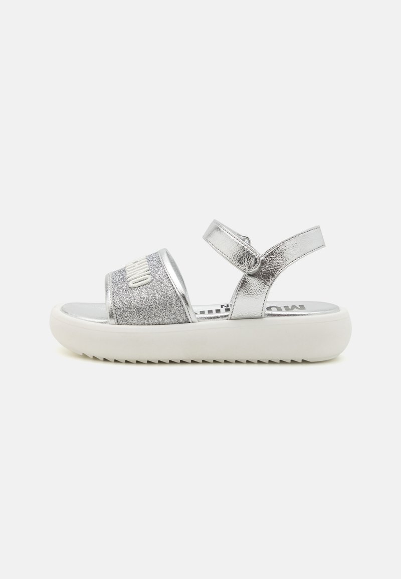 Silver sandaler med glittrande rem och justerbar ankle buckle. Tjock vit gummisula med texturerat mönster för grepp.