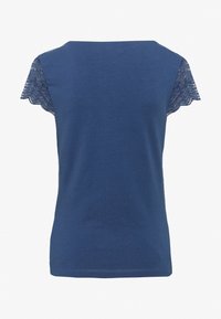 Námořnická modrá tričko s krátkými krajkovými rukávy. Měkká látka, kulatý výstřih a hladký povrch. Má scalloped krajkový okraj na rukávech.
