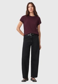 Burgundy kortärmad t-shirt kombinerad med högmidjade svarta vida jeans, kompletterad med ett svart bälte och svarta st studs skor.