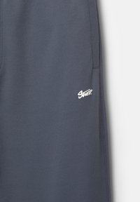 Navyblauwe sweatshirtstof met een zichtbaar logo in het wit. De stof lijkt glad met een gestikte rand, ontworpen voor comfort en pasvorm.