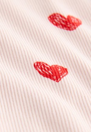 Tissu côtelé rose clair avec deux cœurs rouges brodés, présentant un motif texturé.