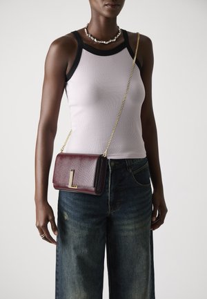 Bordeaux leren schoudertas met een gestructureerde afwerking, gouden hardware en een 'L' accent op de voorkant. Ketting strap bevestigd.