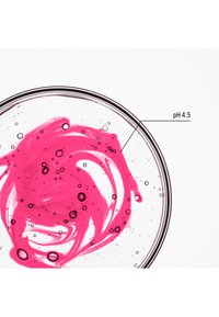 Klar glaspetriskål innehållande en virvlande rosa vätska med bubblor, märkt "pH 4,5." Bakgrunden är enfärgad vit.
