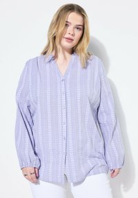 Camisa de botones de lavanda con rayas verticales, patrones florales, mangas largas y un corte relajado. Confeccionada en una tela ligera.