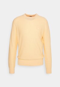 Ljusgul crewneck-tröja med lång ärm, ribbad mudd och en liten fyrkantig logotyp på vänster bröst.