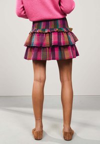 Gonna a balze colorata con strisce viola, rosa e marroni su un tessuto strutturato. L'orlo è rifinito con bordi arricciati.