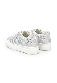Zapatillas deportivas blancas de caña baja con suelas gruesas, cubiertas de brillantes de color plata, vistas desde atrás y en ángulo lateral sobre un fondo blanco.