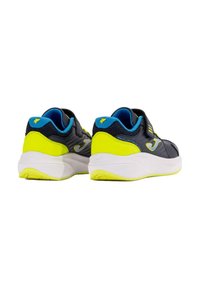 Las zapatillas deportivas negras y amarillas neón cuentan con una parte superior suave, correa ajustable, cuello acolchado y una suela blanca ligera con tracción.