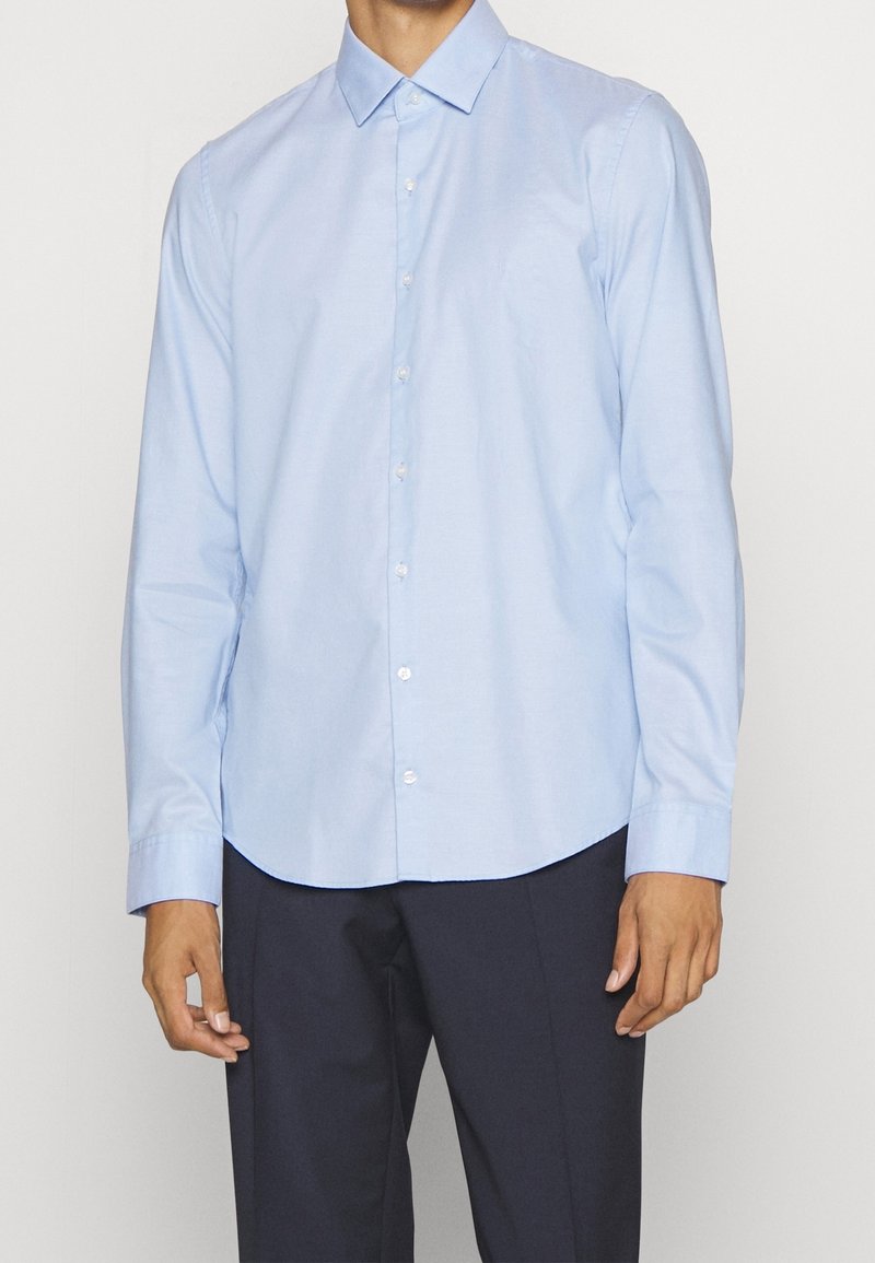 Lichtblauwe langemouwblouse van katoen, met een puntkraag, reguliere pasvorm en een gebogen zoom. Voorzien van witte knopen.