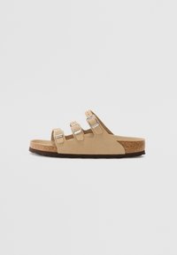 Beige sandals with three adjustable straps and metallic buckles. Cork midsole and textured rubber outsole. Minimalist design and open back.