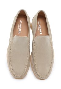 Mocassini in suede beige con una texture liscia, dettagli cuciti e una leggera suola in gomma. Presentano una punta arrotondata e nessun fermo visibile.