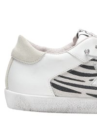 Sneaker bianca con un tallone in suede grigio, presenta un motivo zebra nero e grigio di lato, suola in gomma testurizzata e dettagli con lacci.