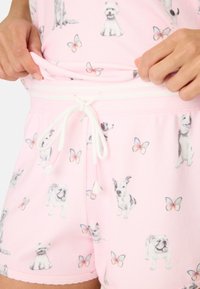 Ljusrosa shorts i mjukt tyg har ett mönster med olika hundar och fjärilar. Midjan har en dragsko med tofsar.