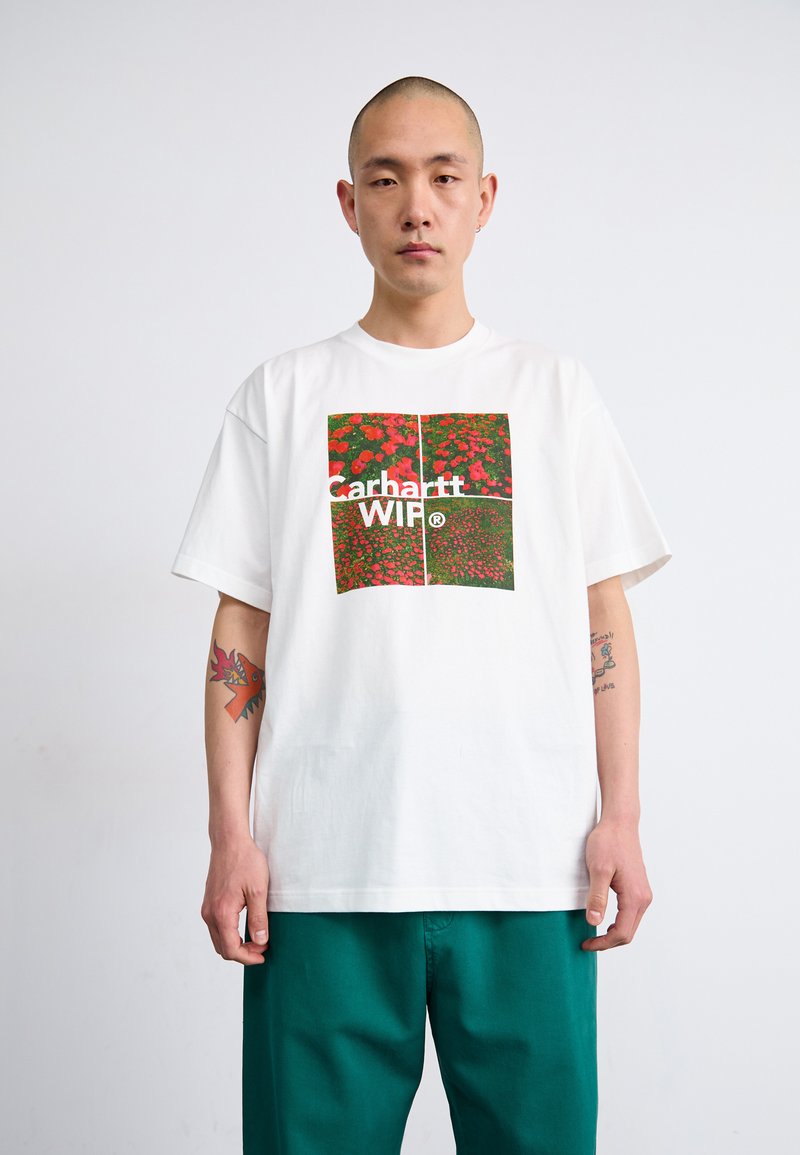 Biele bavlnené tričko s farebnou kvetinovou grafikou a textom "Carhartt WIP". Krátke rukávy, voľný strih, jednoduchý dizajn s okrúhlym výstrihom.
