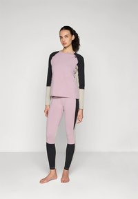 Jasnofioletowa bluzka z długim rękawem z czarnymi i szarymi akcentami, połączona z dopasowanymi legginsami. Gładki, elastyczny materiał, przylegający krój.