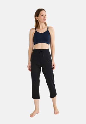 Brassière de sport bleu marine et pantalon court noir. La brassière est équipée de bretelles réglables ; le pantalon possède une taille élastique avec un cordon de serrage. Texture du tissu lisse.