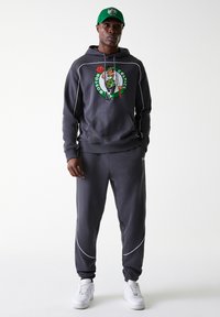 Gray hoodie with a Boston Celtics graphic, featuring white accents and drawstring. Paired with matching gray sweatpants, completed with white sneakers.