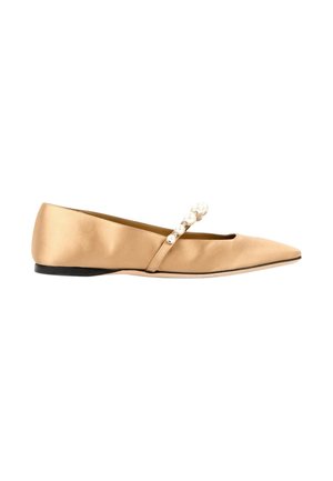 Beige satijnen platte schoen met puntige neus, zwarte zool en een bandje versierd met witte parels dat over de bovenkant loopt.