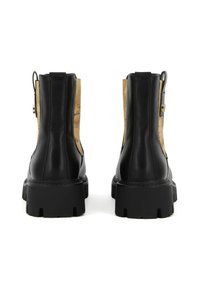 Botas de tobillo de cuero negro con una suela de goma gruesa, que presentan un panel lateral con un diseño beige y una cremallera lateral con un acento dorado.