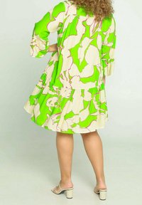 Jurk met bloemenpatroon in levendige groene en beige tinten, met een geplooide rok, driekwart mouwen en een ontspannen pasvorm.