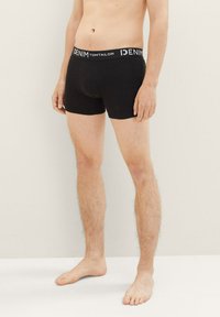 Fekete boxer alsónadrág, puha és rugalmas anyagból. A derekán fehér betűkkel ellátott "DENIM TOM TAILOR" felirattal. Slim fit fazon.