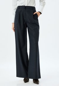 Wijde broek in donkerblauw stoffen met een subtiele textuur, met een hoge taille, voortassen en een losse pasvorm.