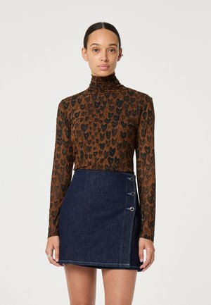 Langsleeve, getailleerde top in bruin met zwarte luipaardprint; gecombineerd met een minirok van donkerdenim met een zijsluiting met knopen en contrasterende zoom.