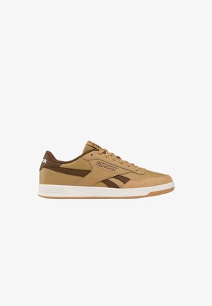 Zapatilla baja de Reebok en tonos marrón claro y marrón con cordones en la parte frontal y suela blanca, logo lateral visible.