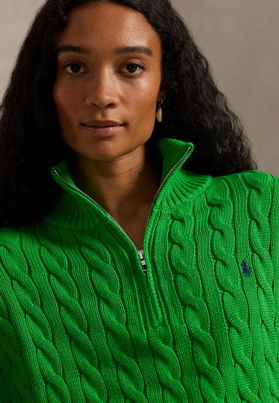 Πράσινο πουλόβερ με ανάγλυφο πλεκτό σχέδιο και φερμουάρ στον ψηλό γιακά. Διαθέτει υφή με σχέδιο και μικρό λογότυπο στο στήθος. Μαλακό υλικό.