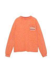 Oranžová dlhá rukávová košeľa s okrúhlym výstrihom, s náprsním vreckom a bielym potlačeným logom "TOYOTA Land Cruiser". Mäkka, jemne štruktúrovaná tkanina.
