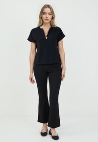 Maglietta nera a maniche corte con scollo a V e dettaglio con bottone dorato, abbinata a pantaloni neri a zampa d'elefante, per un look elegante e sofisticato.