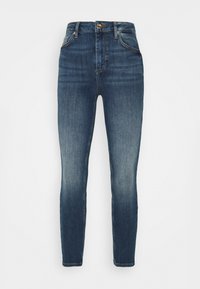 Jeans ajustados en denim azul oscuro, con una textura suave, detalles desgastados en los muslos y un cierre clásico de cremallera con botón.