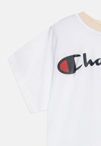 T-shirt bianca in cotone con scollatura beige, grande logo nero e rosso sulla parte anteriore e maniche corte con una texture liscia.