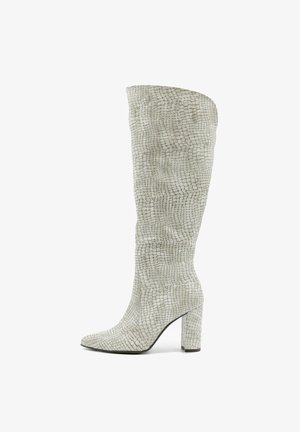 Białe kozaki ze skóry o fakturowanej powierzchni do kolan, z wyraźnie zarysowaną sylwetką, spiczastym noskiem i grubym obcasem, charakteryzujące się wzorem w kratę.