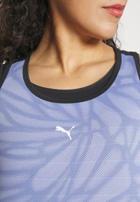 Světle modré sportovní tričko z prodyšné tkaniny s černými akcenty, s logem na hrudi, ukazující texturovaný vzor a kulatý výstřih.