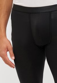Black athletic leggings with a smooth texture, elastic waistband, and seam detailing. Designed for comfort and fit during physical activity.