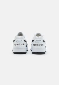 Adidași din piele albă cu accente negre, vârf rotund, design low-top și talpă din cauciuc texturat. Prezintă branding Reebok pe toc.
