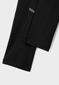 Czarne legginsy sportowe wykonane z gładkiego, elastycznego materiału z wyraźnymi szwami i lekko zwężanym dołem.