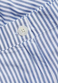 Blå och vit randig tyg med knappstängning, med en slät yta och prydliga sömmar.