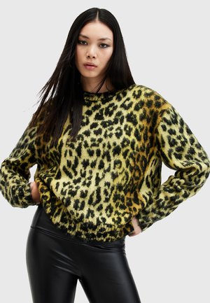 Leopard print sweater in yellow and black, featuring a loose fit, long sleeves, and a ribbed neckline; paired with black leggings.