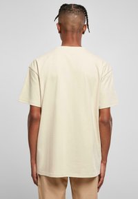Beige bomull t-skjorte med en avslappet passform, kort erm og rett hem. Har en jevn tekstur og rund hals.
