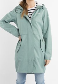 Mintgrön vattentät jacka med huva, med tryckknappar, sidofickor och en dragkedja på vänster ficka. Ränder på innerfodret.