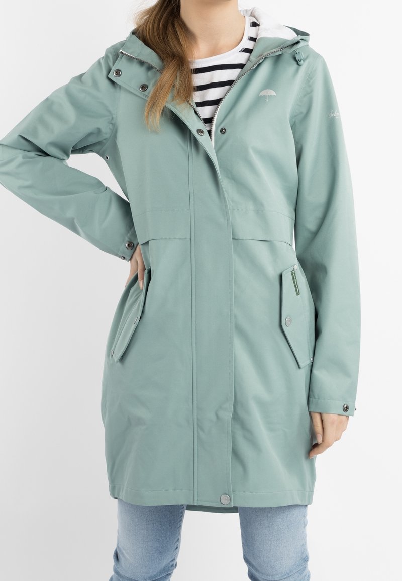 Mintgrön vattentät jacka med huva, med tryckknappar, sidofickor och en dragkedja på vänster ficka. Ränder på innerfodret.