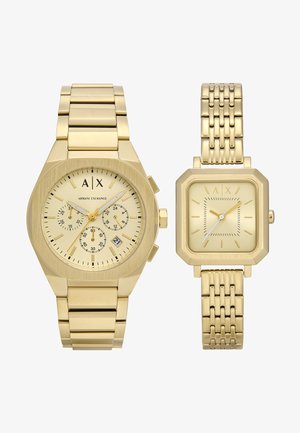 Guldtonet ur sæt med en chunky oktagonal urkasse med chronograf-dials og et rektangulært mesh-bånd. Begge har minimalistiske designs.