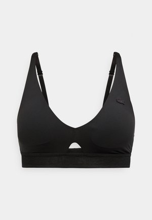 Soutien-gorge sans fil noir avec bretelles ajustables, bonnets souples, bande élastique sous la poitrine et petit logo de la marque sur le bonnet gauche.