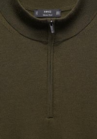 Pull-over en laine mérinos vert foncé avec col montant et fermeture éclair sur un quart de longueur. Tricot côtelé texturé sur l'ensemble. Étiquette de la marque attachée.
