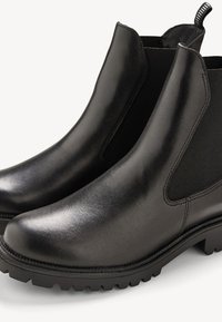 Bottines Chelsea en cuir noir avec panneaux élastiques sur les côtés et semelle en caoutchouc texturé, dotées d'un bout arrondi et de détails de couture minimalistes.
