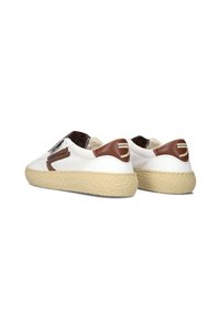 White canvas sneakers with brown accents, textured rubber sole, and woven detail on the heel. Features a rounded toe and low-top design.