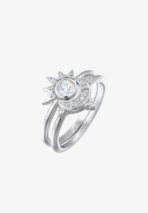 Bague en argent avec un motif de soleil et de lune, ornée d'une pierre centrale claire et de petites pierres autour, bande lisse avec finition polie.