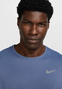 Herrenblaues Nike-T-Shirt mit rundem Ausschnitt und kurzen Ärmeln; verfügt über ein kleines graues Logo auf der Brust, gefertigt aus einem strukturierten Stoff.